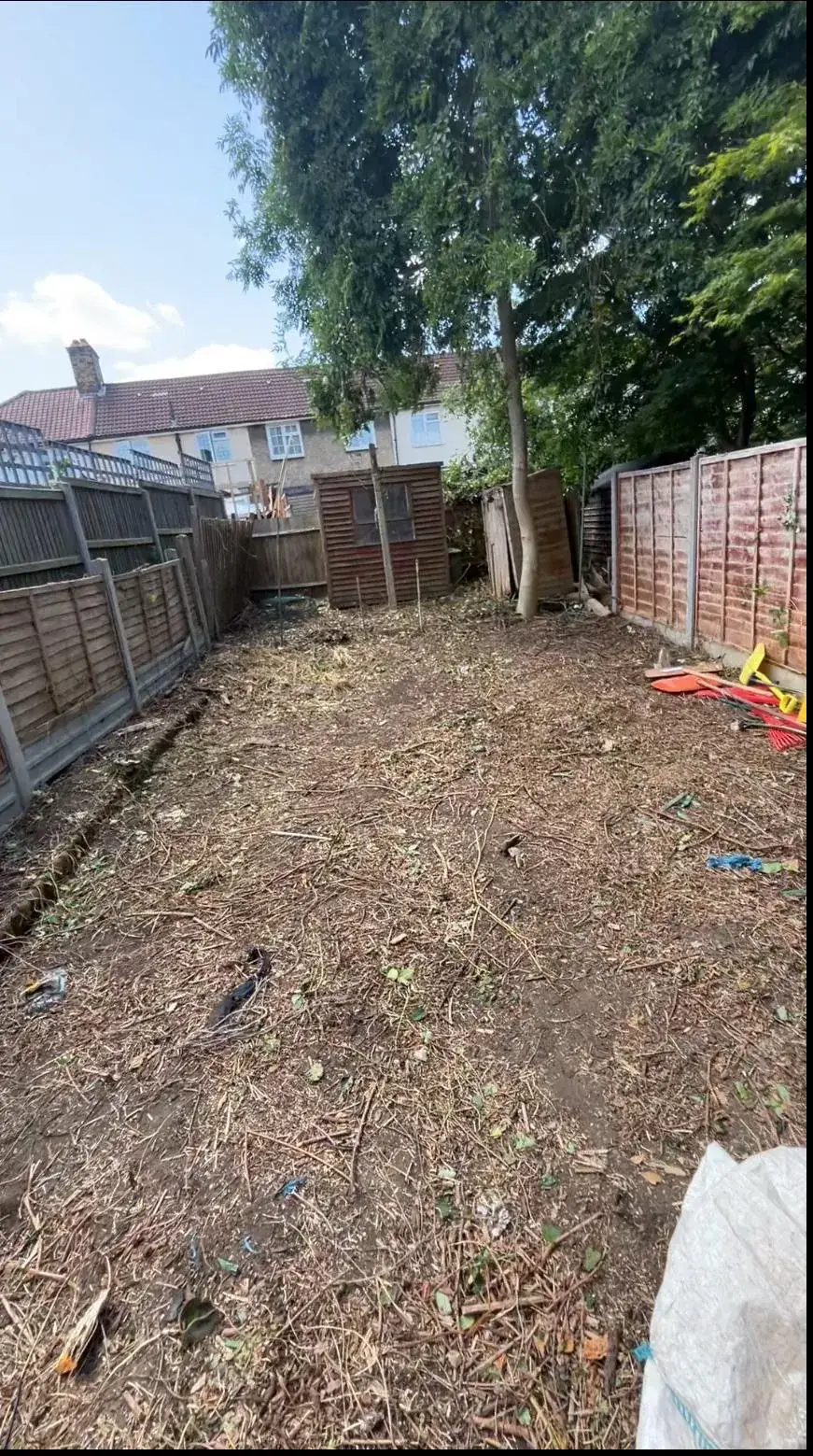An overgrown garden cleared back to bare, workable ground