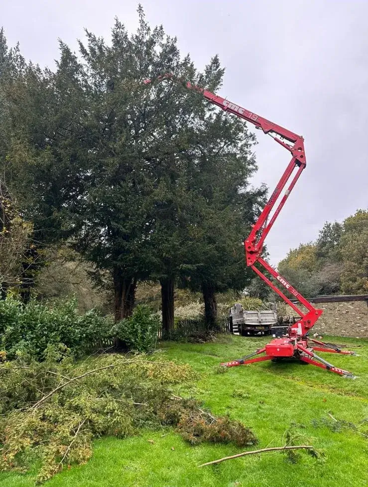 A red cherry picker in the middle of a field.