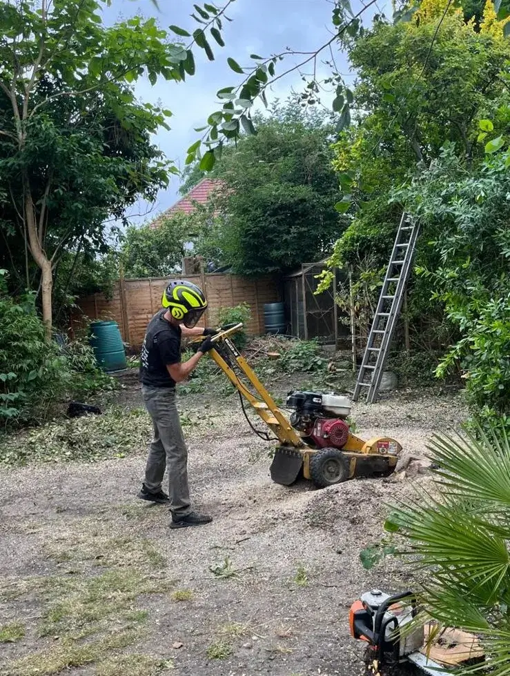 A man in a helmet is using a small lawn mower.